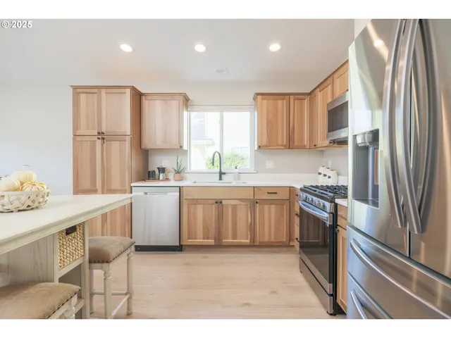 a kitchen with a sink cabinets stainless steel appliances and a window