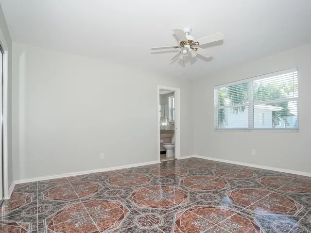 a view of an empty room with window and chandelier fan