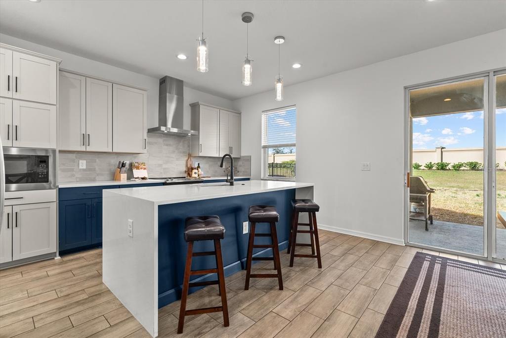8330 Abalone Loop Palmetto, FL 34221 - Photo 4 of 45 a kitchen with kitchen island granite countertop wooden floors and white cabinets
