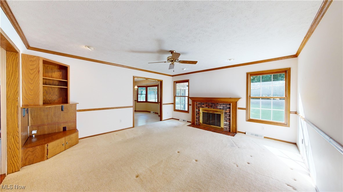 30102 Rickey Lane Wickliffe, OH 44092 - Photo 11 of 44 Unfurnished living room featuring a fireplace, a textured ceiling, ceiling fan, light carpet, and ornamental molding