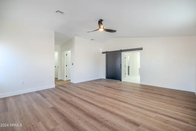 a view of empty room with wooden floor and ceiling fan