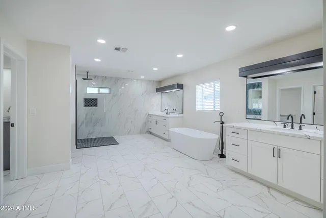 a large white bathroom with a granite countertop sink a toilet a mirror and bathtub