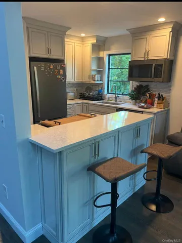 a kitchen with stainless steel appliances granite countertop a sink dishwasher a stove a refrigerator a microwave oven and a dining table with wooden cabinet