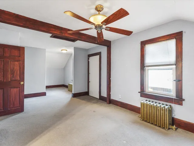 an empty room with ceiling fan and windows