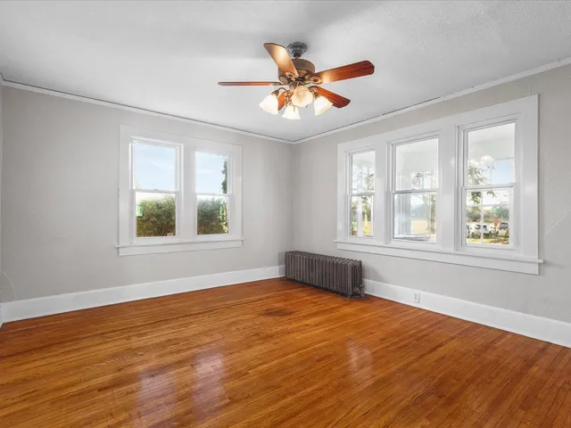 a view of an empty room with wooden floor and a window