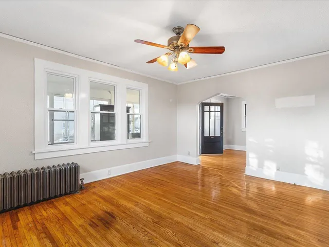 a view of an empty room with window and wooden floor