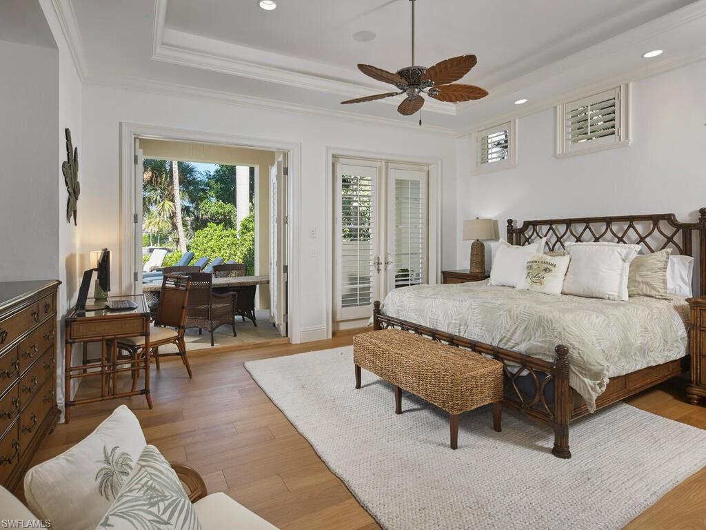 377 Pirates Bight Naples, FL 34103 - Photo 19 of 44 a spacious bedroom with a bed a couch and a chandelier