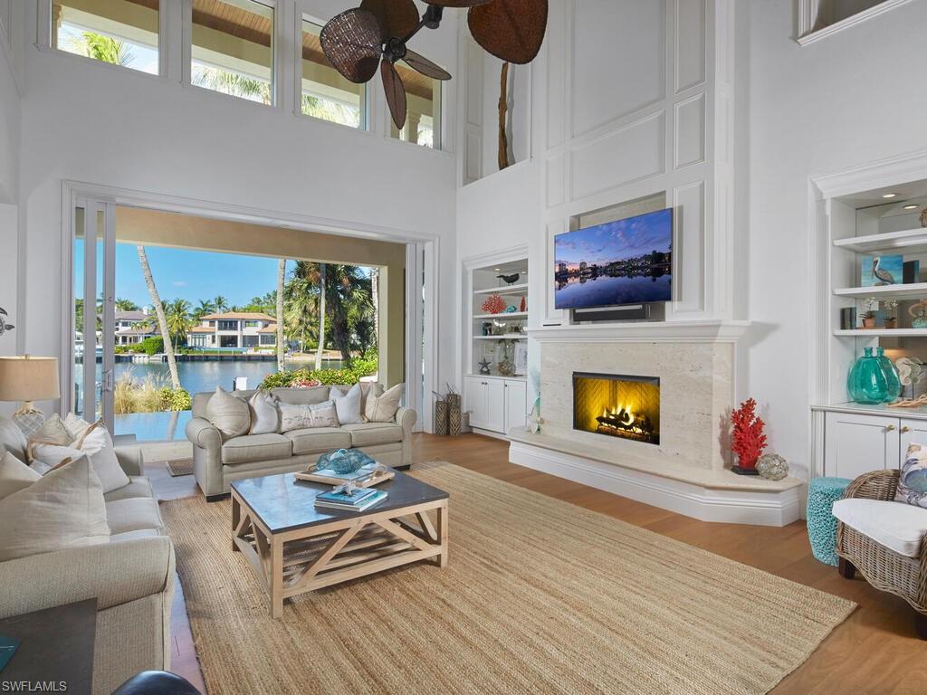 377 Pirates Bight Naples, FL 34103 - Photo 8 of 44 a living room with furniture a flat screen tv and a fireplace