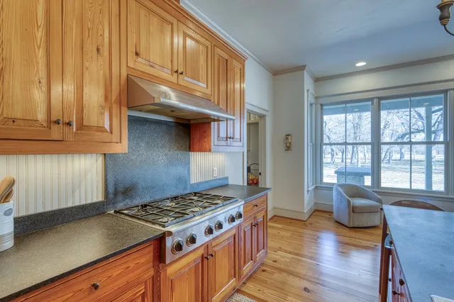 a kitchen with granite countertop a stove and a wooden cabinets