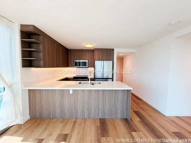 a large kitchen with stainless steel appliances a large counter top a stove and a refrigerator