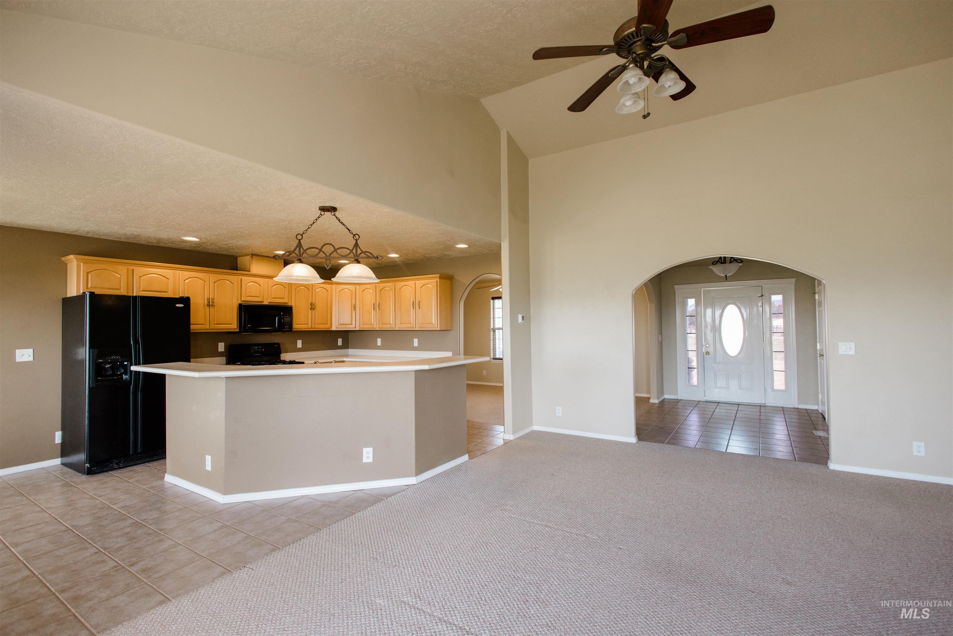 1571 Southeast Hamilton Road Mountain Home, ID 83647 - Photo 50 of 50 Kitchen featuring light tile patterned floors, black appliances, light countertops, light wood finish cabinets, and open floor plan