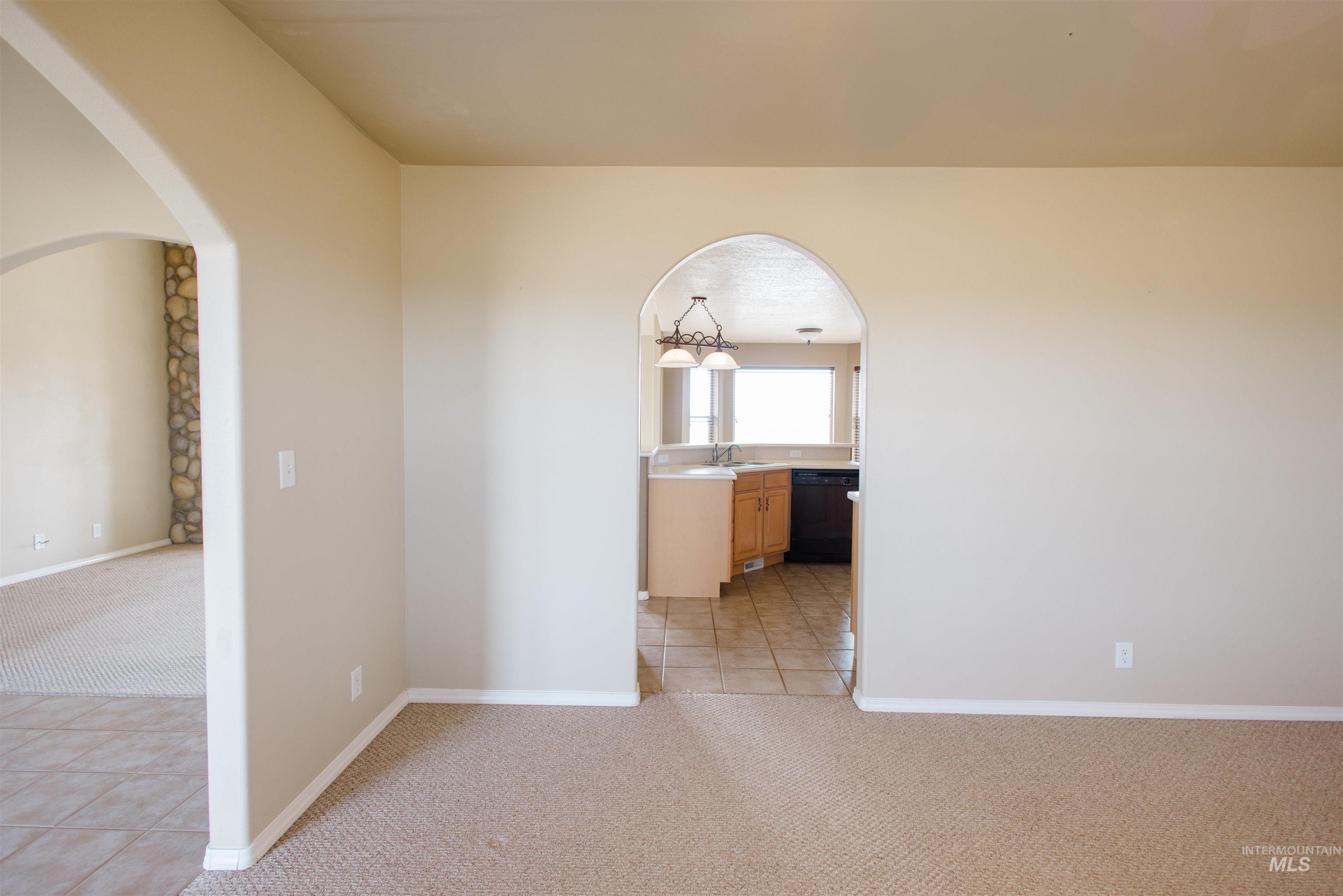 1571 Southeast Hamilton Road Mountain Home, ID 83647 - Photo 11 of 50 Unfurnished room featuring light colored carpet, light tile patterned flooring, and arched walkways