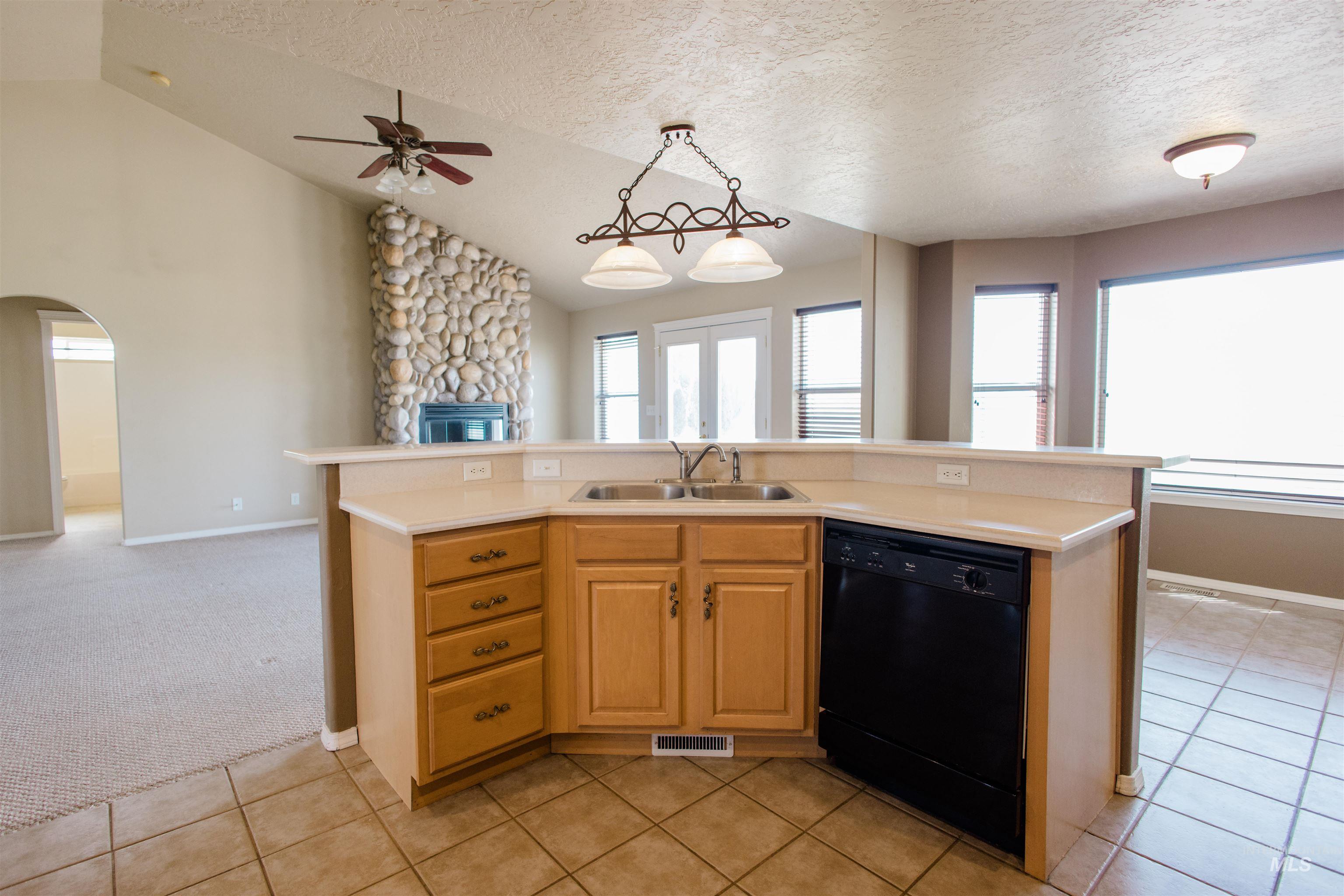 1571 Southeast Hamilton Road Mountain Home, ID 83647 - Photo 48 of 50 Kitchen with open floor plan, a kitchen island with sink, black dishwasher, light colored carpet, and hanging light fixtures