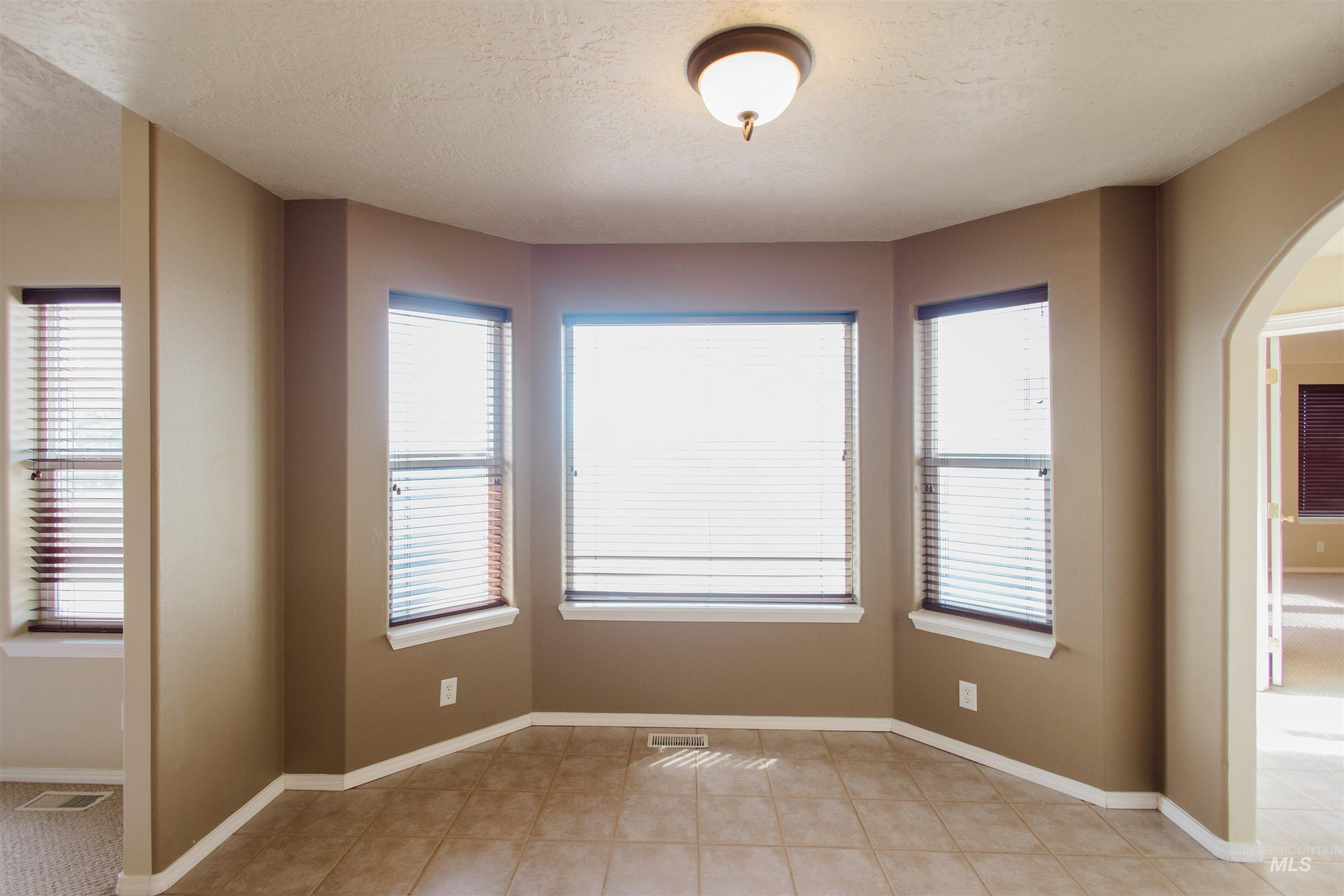 1571 Southeast Hamilton Road Mountain Home, ID 83647 - Photo 4 of 50 Unfurnished room with arched walkways, healthy amount of natural light, and a textured ceiling