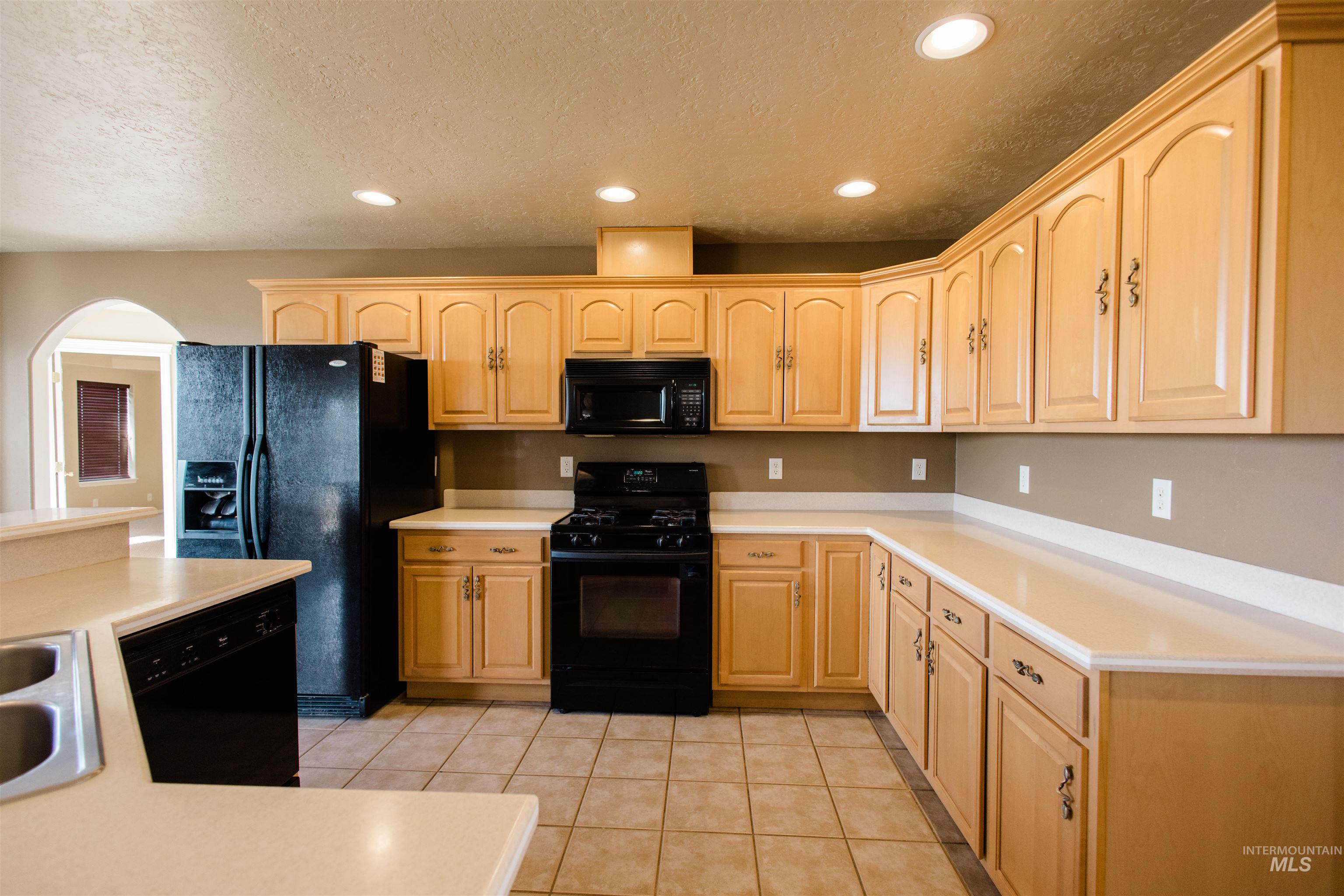 1571 Southeast Hamilton Road Mountain Home, ID 83647 - Photo 5 of 50 Kitchen with black appliances, light countertops, recessed lighting, light wood finish cabinets, and a textured ceiling
