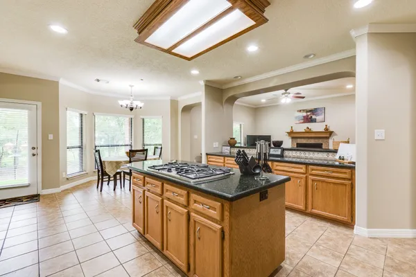 a kitchen with stainless steel appliances granite countertop a stove top oven a sink a dining table and chairs with wooden floor