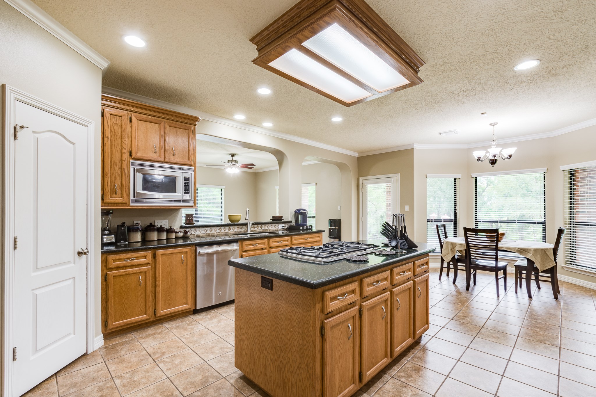 507 Oaks Grande Road Baytown, TX 77523 - Photo 19 of 50 a kitchen with stainless steel appliances granite countertop a stove top oven a sink a dining table and chairs with white cabinets