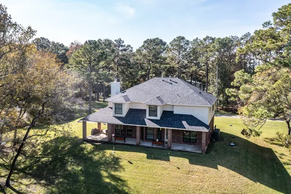 an aerial view of a house with swimming pool and large trees