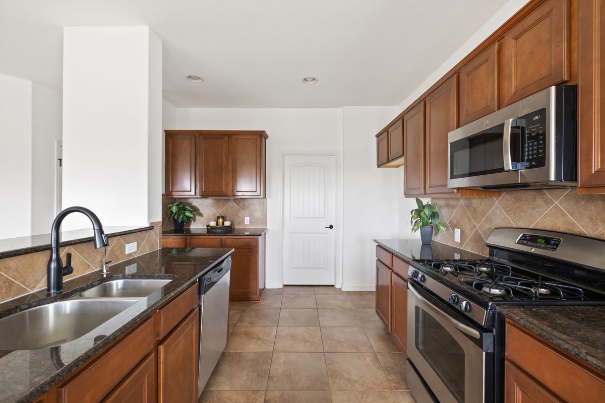 407 Stone View Trail Austin, TX 78737 - Photo 18 of 40 a kitchen with stainless steel appliances granite countertop a sink stove top oven and refrigerator