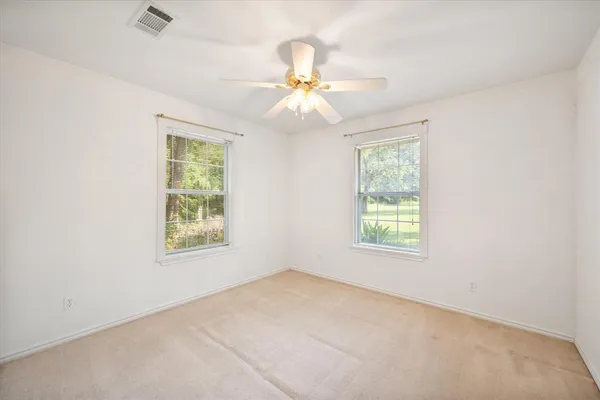 an empty room with windows and fan