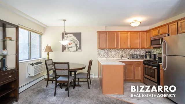 a kitchen with stainless steel appliances granite countertop a stove a refrigerator a dining table and chairs with wooden floor