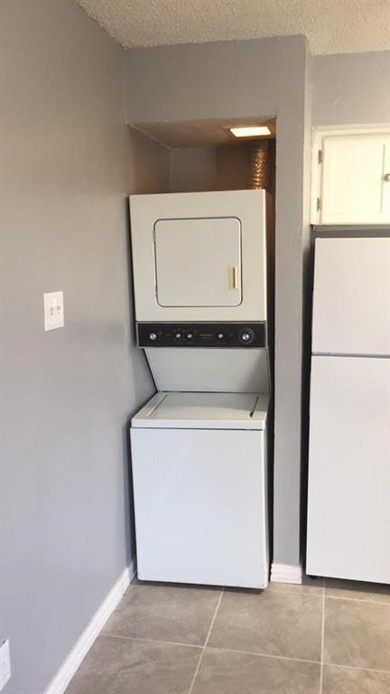 9809 Walnut Street, Unit E305 Dallas, TX 75243 - Photo 13 of 16 Laundry area with light tile patterned floors, a textured ceiling, and stacked washer / dryer
