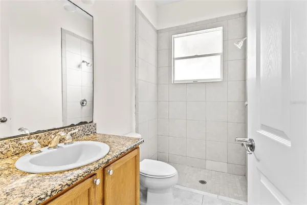 a bathroom with a granite countertop sink toilet and shower