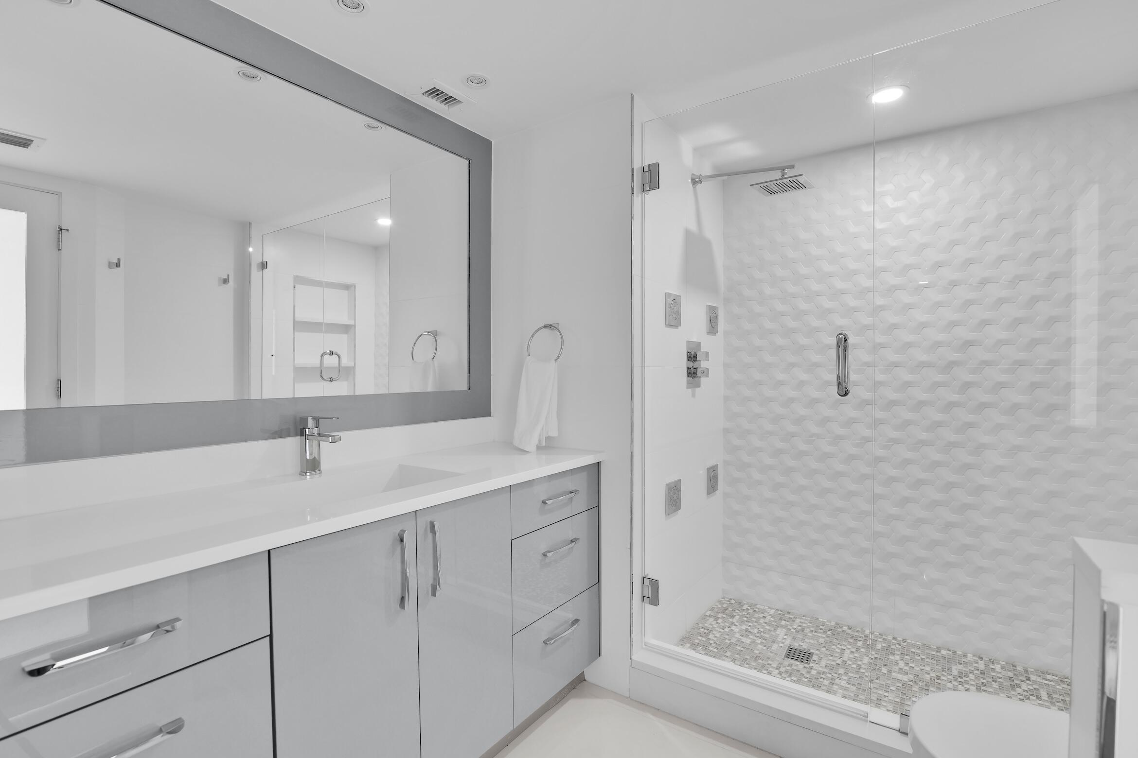 550 South Ocean Boulevard, Unit PH06 Boca Raton, FL 33432 - Photo 22 of 62 a bathroom with a shower sink and mirror