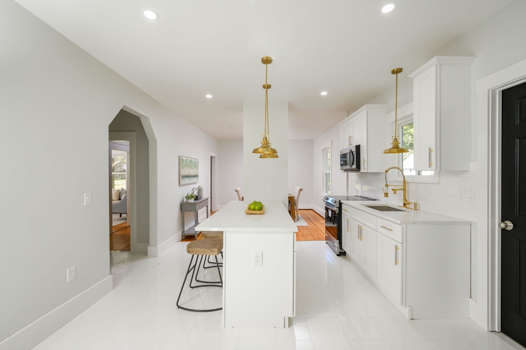 120 Broadway Hanover, MA 02339 - Photo 6 of 35 a kitchen with stainless steel appliances granite countertop a sink a stove a refrigerator cabinets and living room view