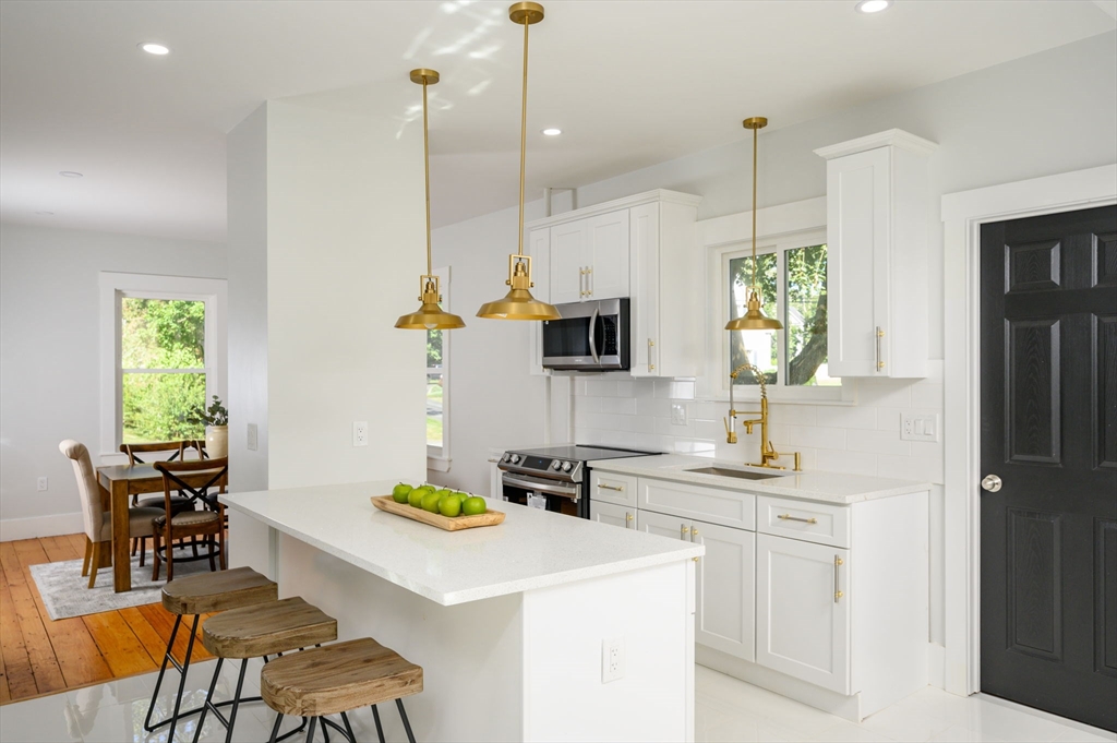 120 Broadway Hanover, MA 02339 - Photo 8 of 35 a kitchen with a sink a counter top space and living room view