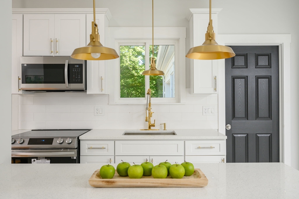 120 Broadway Hanover, MA 02339 - Photo 10 of 35 a kitchen with a stove a sink and a microwave