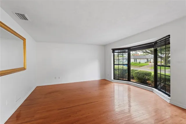 a view of empty room with wooden floor and fan