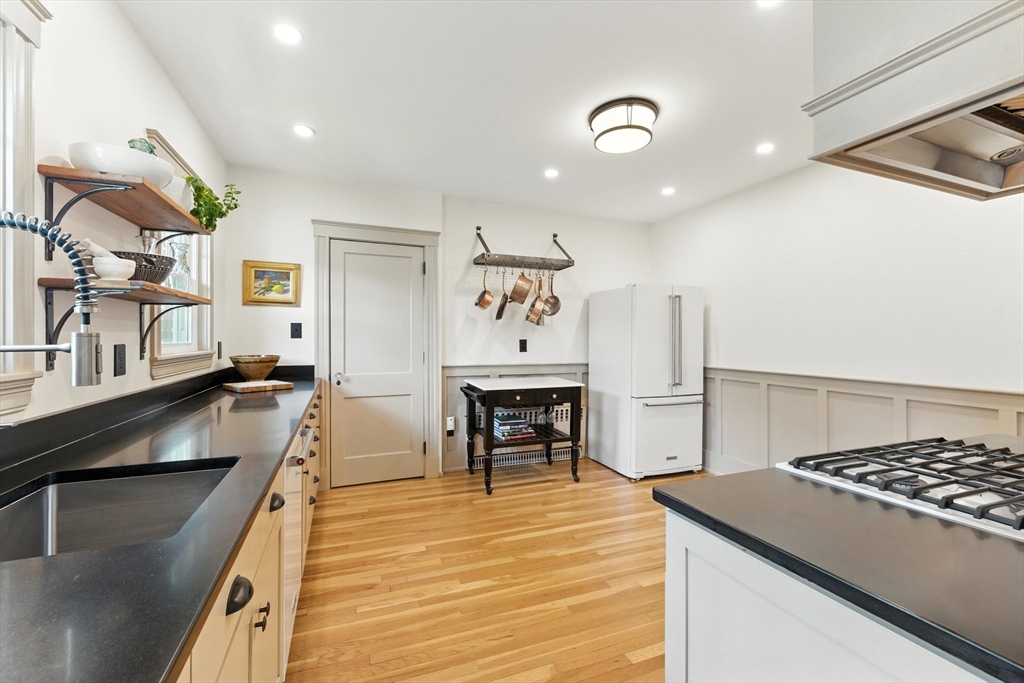 29 Hillcrest Circle, Unit 2 Watertown, MA 02472 - Photo 12 of 36 a kitchen with stainless steel appliances granite countertop a stove top oven a sink a dining table and chairs with wooden floor