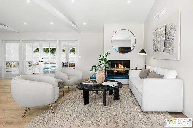 a living room with furniture a mirror a lamp and wooden floor