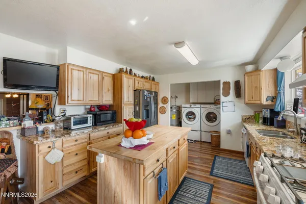 a kitchen with stainless steel appliances kitchen island granite countertop a stove refrigerator a sink dishwasher and a fireplace with wooden floor