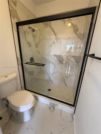 a white toilet sitting next to a shower in a bathroom