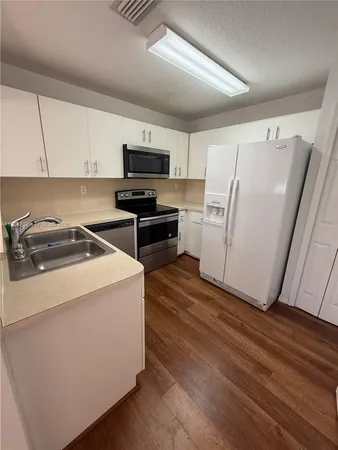 a kitchen with a refrigerator a stove top oven a sink and dishwasher with wooden floor
