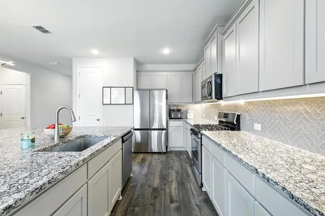 a kitchen with stainless steel appliances granite countertop a sink stove and refrigerator