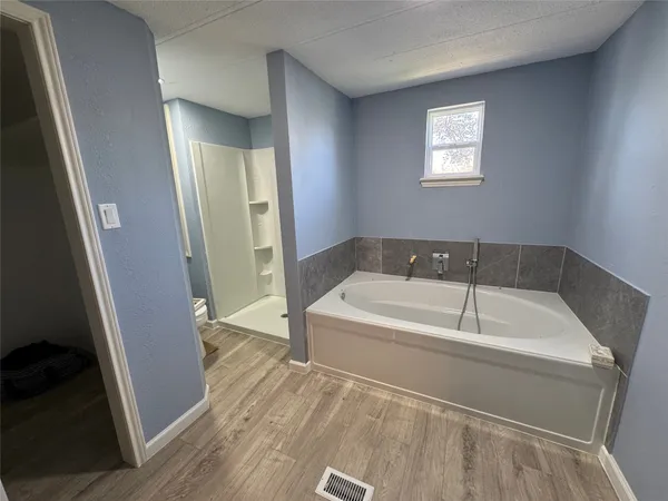 a spacious bathroom with a tub shower and a sink
