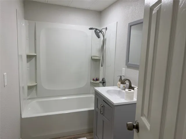 a bathroom with a tub sink shower and two mirror