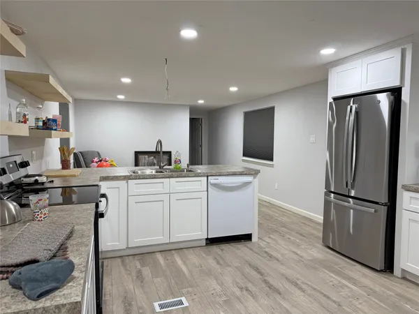 a kitchen with a refrigerator and white cabinets