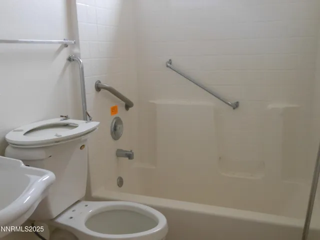a bathroom with a granite countertop toilet and a bathtub