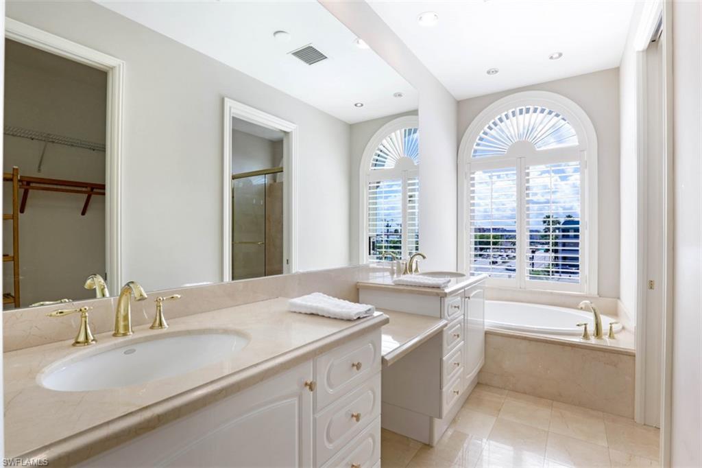 900 5th Avenue South, Unit 301 Naples, FL 34102 - Photo 11 of 17 a bathroom with double vanity sinks a large mirror and a bathtub next to a window