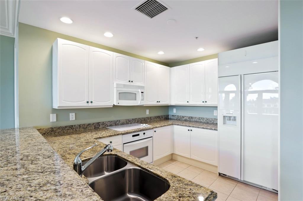 900 5th Avenue South, Unit 301 Naples, FL 34102 - Photo 7 of 17 a kitchen with granite countertop a sink stainless steel appliances and cabinets
