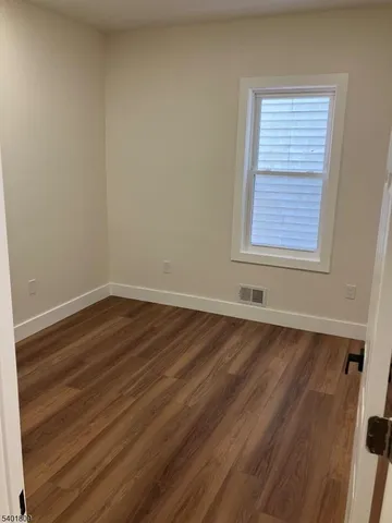 a view of a room that has wooden floor and cabinets