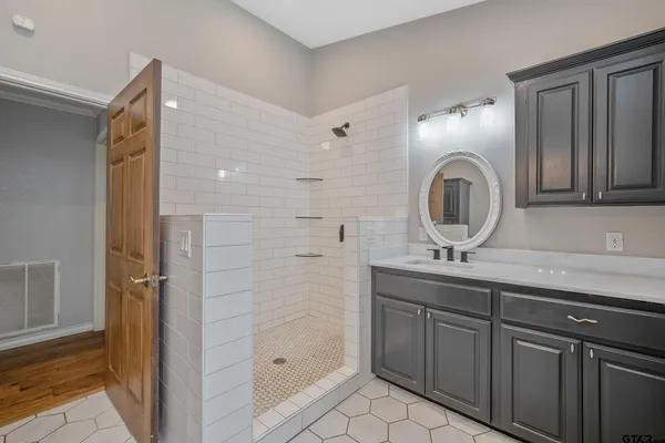 a bathroom with a granite countertop sink a mirror and shower