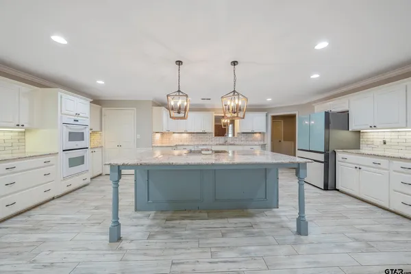 a large kitchen with granite countertop a large counter top and stainless steel appliances