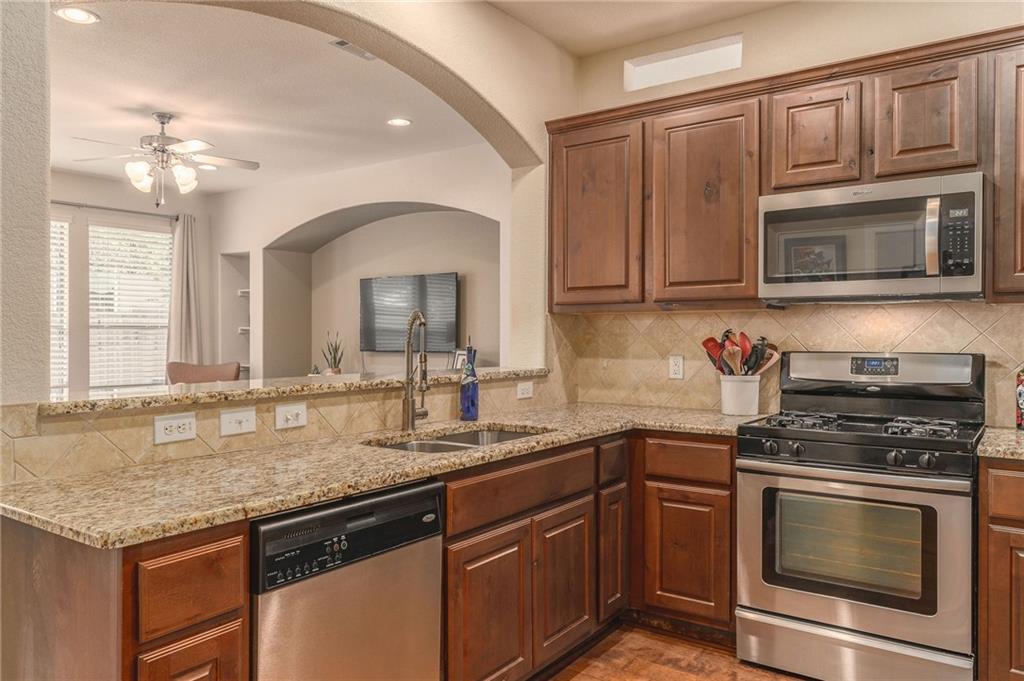 6708 Menchaca Road, Unit 14 Austin, TX 78745 - Photo 13 of 22 Kitchen featuring granite countertops, wood-finish cabinetry, stainless steel appliances, and a tiled backsplash