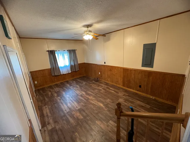 an empty room with chandelier fan and windows