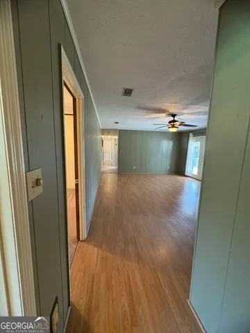 an empty room with a chandelier fan and a window